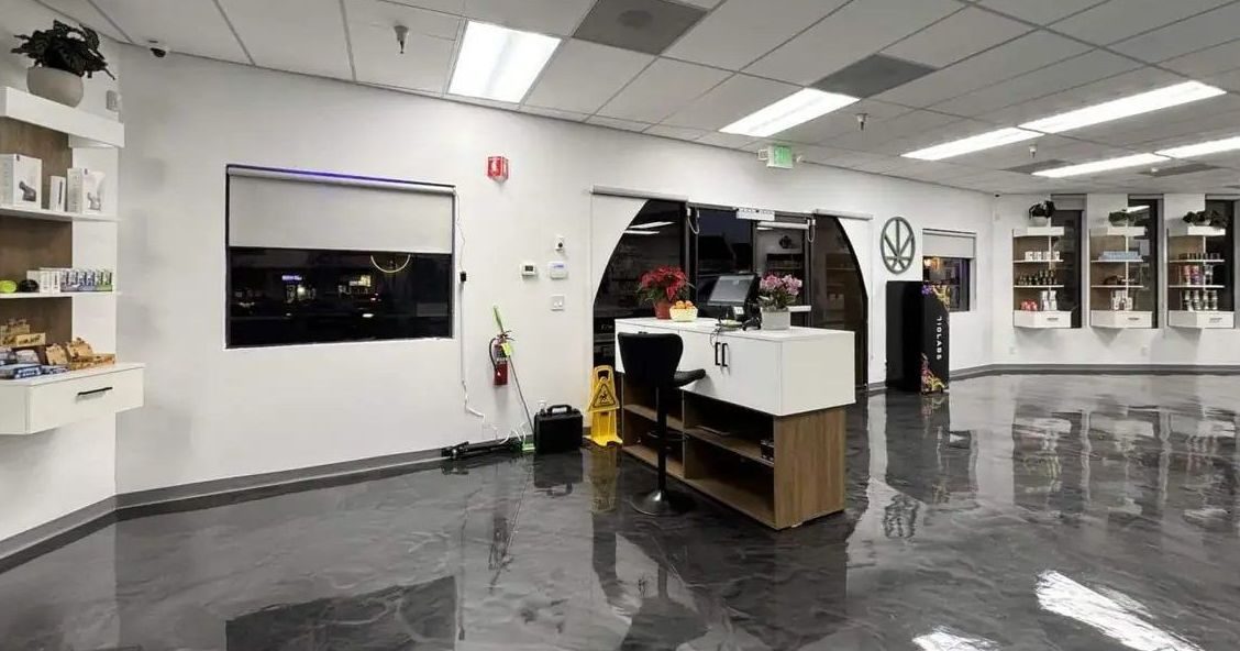 Spacious dispensary interior with polished floors, white counter, and wall displays